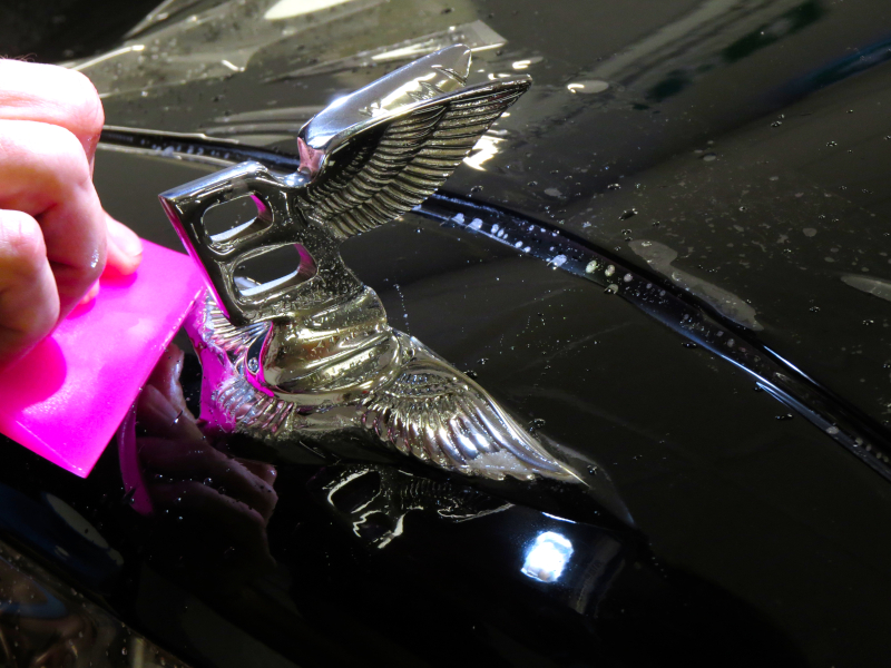 Applicazione della pellicola protettiva auto attorno al logo Bentley sul cofano